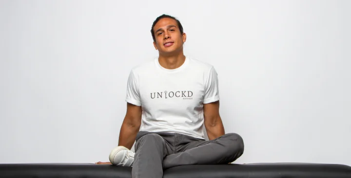 Man wearing "unlockd" shirt sitting on a sofa